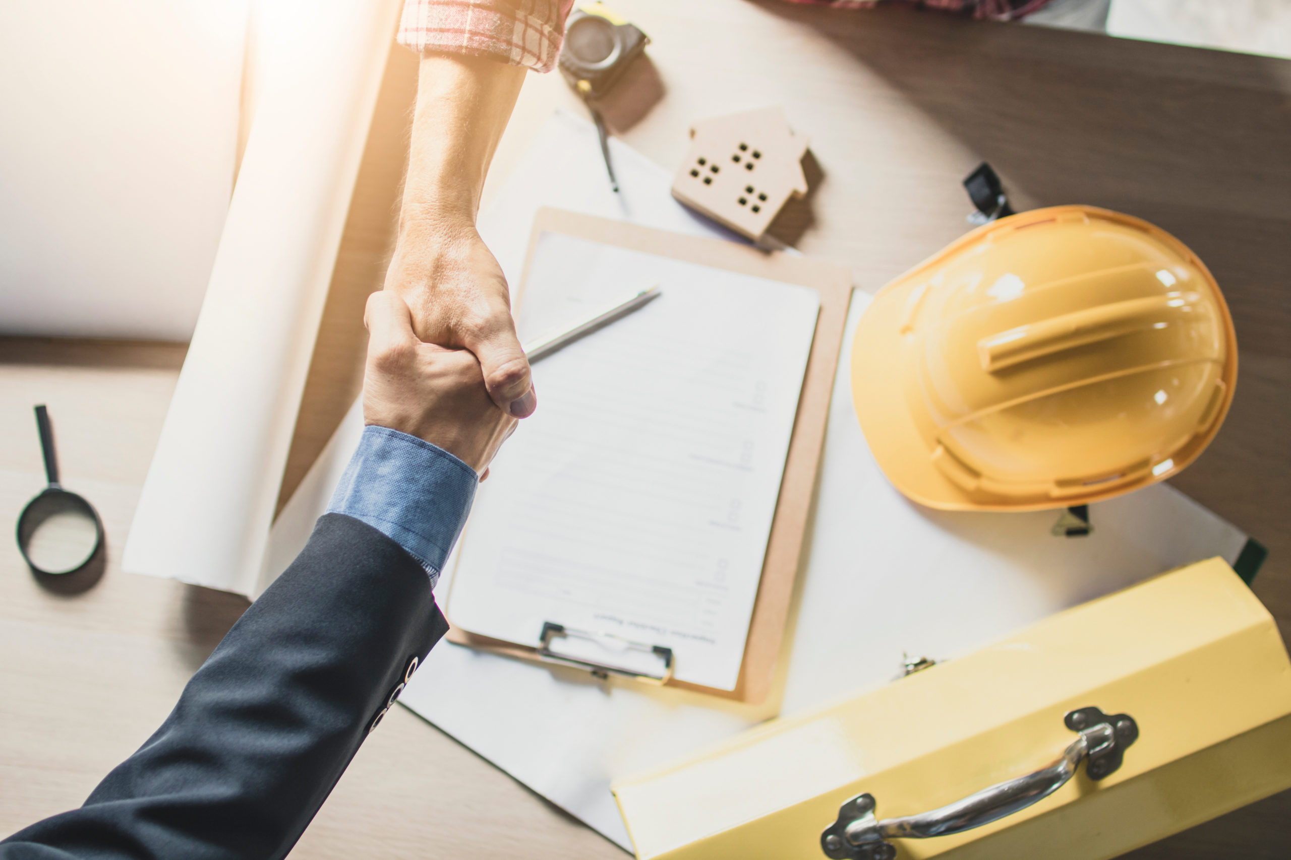 Top view of engineer and businessman shake hands on working tabl